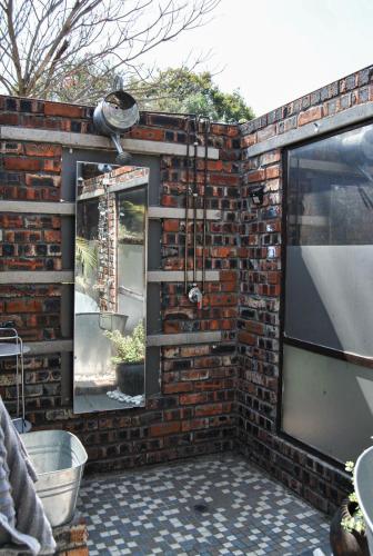 a brick wall with a shower and a mirror at Yolandré in Rustenburg