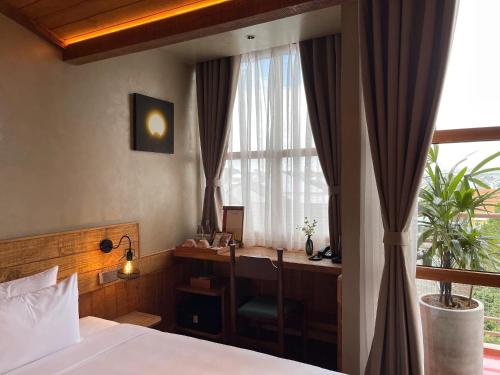 a bedroom with a bed and a desk and a window at The Pink Boutique Hotel in Da Lat