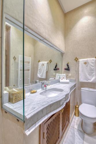 a bathroom with a sink and a toilet and a mirror at Palais Tara & Spa in Marrakech