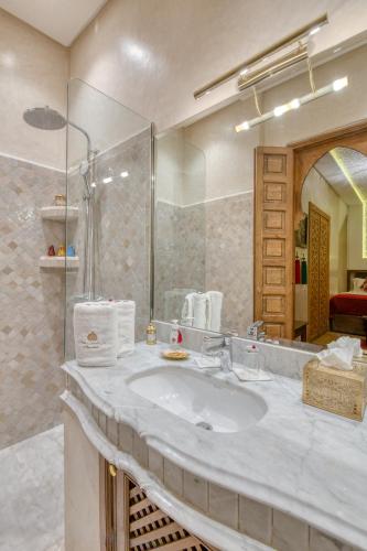 a bathroom with a sink and a large mirror at Palais Tara & Spa in Marrakech