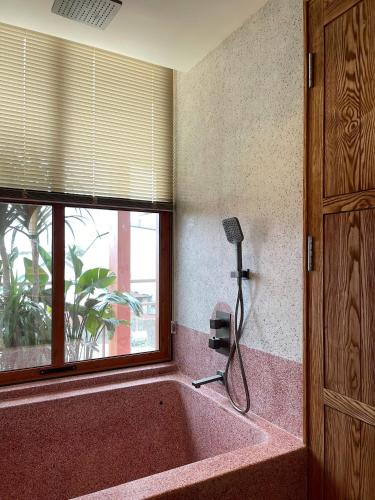a bath tub in a room with a window at The Pink Boutique Hotel in Da Lat
