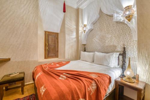 a bedroom with a bed with an orange blanket at Palais Tara & Spa in Marrakech