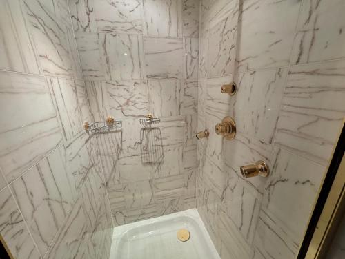 a white marble bathroom with a shower and a toilet at The Bishop in London