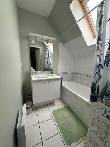 une salle de bain avec un lavabo, une baignoire et un miroir dans l'établissement Maison de 82m2 proche du Mans avec parking privé, à Ruaudin