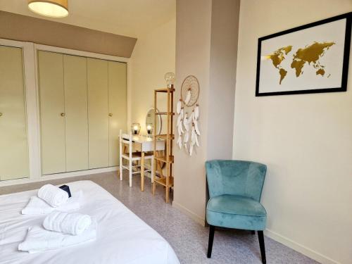 ein Schlafzimmer mit einem Bett und einem blauen Stuhl in der Unterkunft Les Oyats in Les Pieux