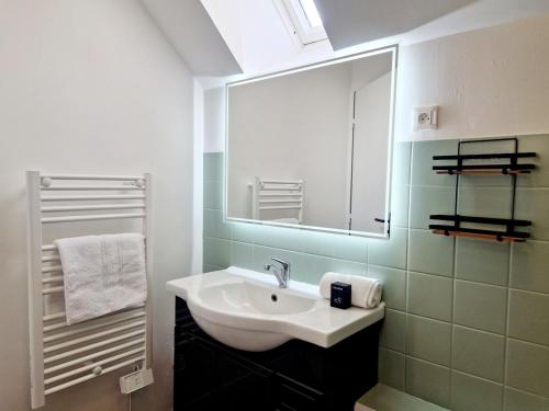 ein Badezimmer mit einem weißen Waschbecken und einem Spiegel in der Unterkunft Les Oyats in Les Pieux