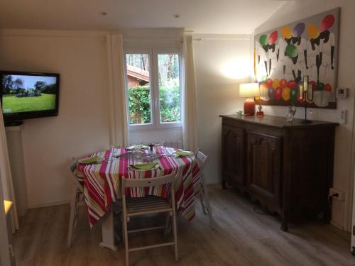 a dining room with a table with chairs and a television at Chalet grand confort Bassin d'Arcachon in La Teste-de-Buch