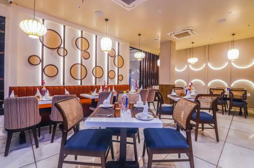 a restaurant with tables and chairs and chandeliers at Hotel Godwin Deluxe - Free Airport Pick-Up in New Delhi