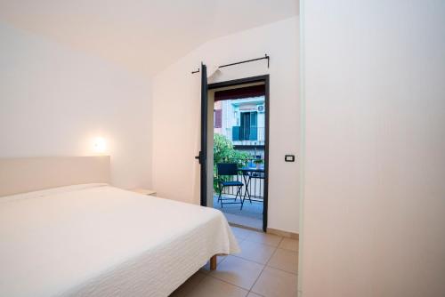 a bedroom with a bed and a door leading to a balcony at Residence Stella Dell'Est in Bari Sardo
