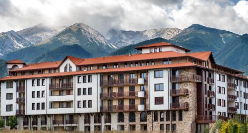 a large building with mountains in the background at Grand Royale Apartment Complex & Spa in Bansko