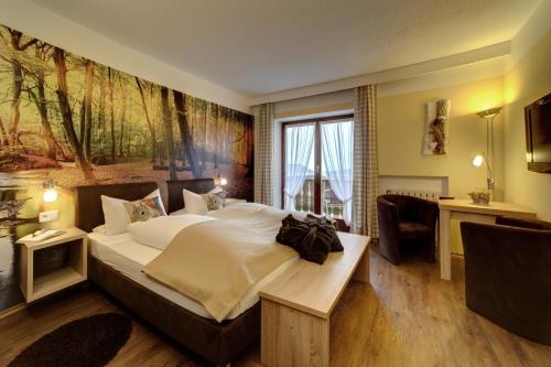 a bedroom with a large bed with a large painting on the wall at Zur neuen Post Landgasthof in Herzogsreut