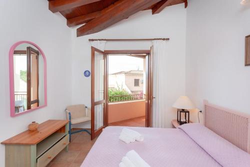 a bedroom with a bed and a desk and a window at Villetta Perla Marina 2 in San Teodoro
