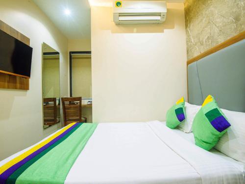 a bedroom with a white bed with green and colorful pillows at Treebo Amber Imperial in Mumbai