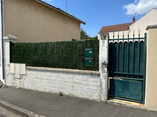 une porte menant à une maison dotée d'une clôture verte dans l'établissement Charmant studio proche centre ville d’Orléans, à Orléans