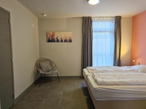 ein Schlafzimmer mit einem Bett und einem Stuhl und einem Fenster in der Unterkunft Vakantiehuis de Reiger SE15 in Serooskerke
