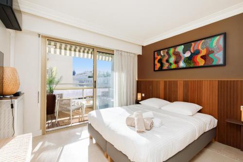 une chambre avec un grand lit et un balcon dans l'établissement Le Palais Royal Elégant Confortable -Balcon 100 mètres Croisette, à Cannes