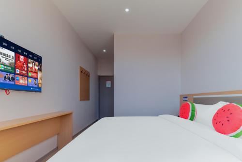 a bedroom with a bed with a tv on the wall at Beijing Watermelon Journey Hotel - Daxing Airport in Beijing