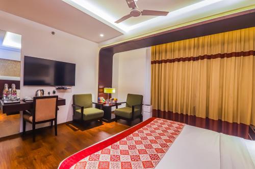 a hotel room with a bed and a desk and a television at Hotel Godwin Deluxe - Free Airport Pick-Up in New Delhi