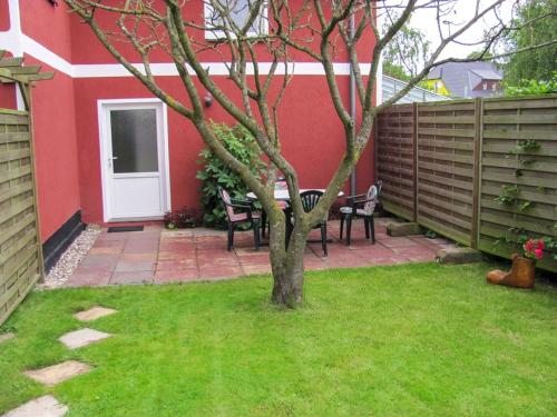 a patio with chairs and a tree in a yard at Ferienwohnungen am Bach in Marlow