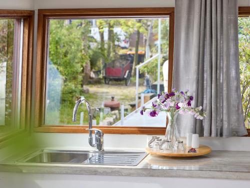 a kitchen sink with a window and a vase of flowers at Your Houseboat Amsterdam in Amsterdam