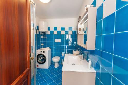 a blue tiled bathroom with a toilet and a sink at Villetta Perla Marina in San Teodoro