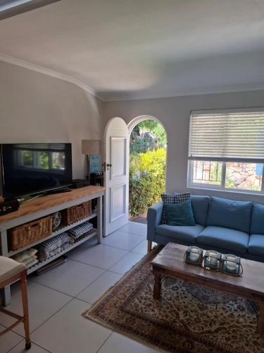 a living room with a blue couch and a tv at Rising Tide in Fish hoek