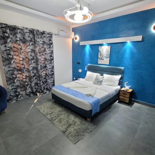 a bedroom with a large bed with a blue wall at Chambres d'hôtes saly in Saly Portudal