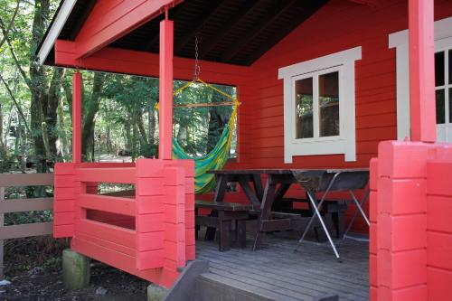 a red house with a picnic table on a deck at PICA Fujiyoshida in Fujiyoshida
