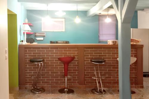 une cuisine avec un comptoir en briques et des tabourets dans l'établissement Maison cosy avec grand jardin, Charny-Orée-de-Puisaye, à Les Jubliers