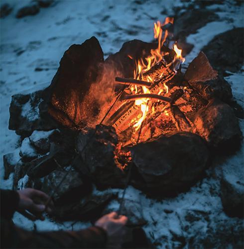 a person is standing around a campfire at Stuga nära Ullared Mitt i Åkulla bokskogar in Rolfstorp