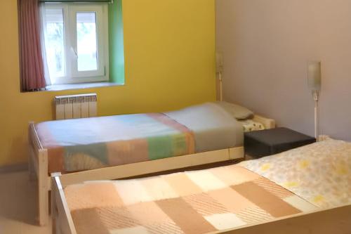 deux lits dans une chambre avec une fenêtre dans l'établissement Maison cosy avec grand jardin, Charny-Orée-de-Puisaye, à Les Jubliers