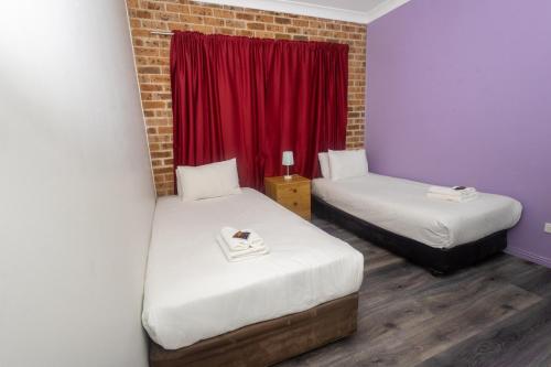 a room with two beds and a red window at Gosford Inn Motel in Gosford