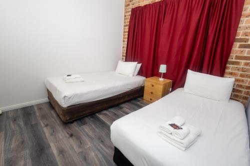 two beds in a room with a red curtain at Gosford Inn Motel in Gosford