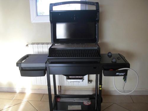 a black barbecue grill on a stand in a room at Gîte du Ranc de Figère in Labeaume