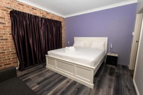 a bedroom with a white bed and a brick wall at Gosford Inn Motel in Gosford