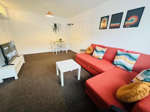 a living room with a red couch and a table at Luton Parkway Apartment-4 guests- free parking in Luton
