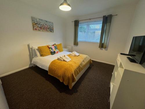 a bedroom with a bed with a yellow blanket and a tv at Luton Parkway Apartment-4 guests- free parking in Luton