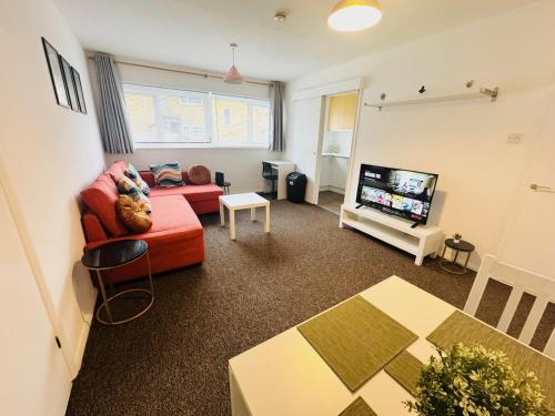 a living room with a red couch and a flat screen tv at Luton Parkway Apartment-4 guests- free parking in Luton