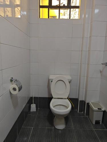 a small bathroom with a toilet and a window at Roza Guest House in Naivasha