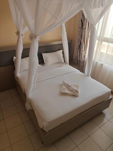 a bed with white sheets and a pair of towels on it at Roza Guest House in Naivasha