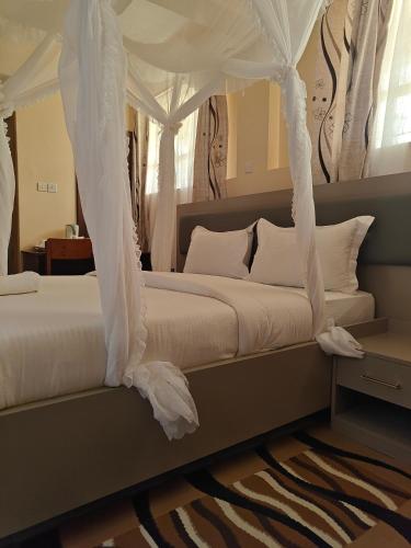 a bedroom with a canopy bed with white sheets and pillows at Roza Guest House in Naivasha