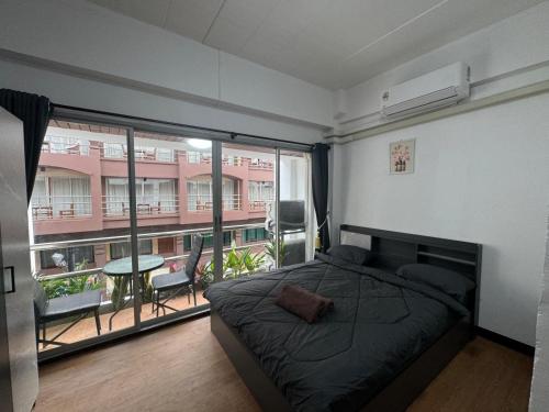 a bedroom with a bed and a large window at Noorjahan Guesthouse Pattaya in Pattaya