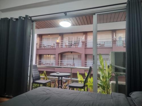 a room with a bed and a balcony with tables and chairs at Noorjahan Guesthouse Pattaya in Pattaya