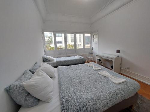 a white bedroom with a bed and a desk at Don Alvares in Lisbon