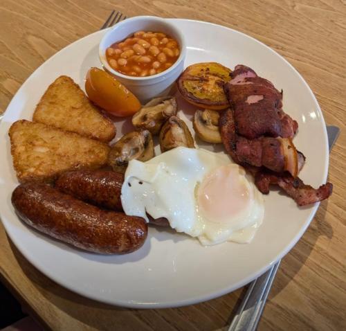 a plate of breakfast food with sausage eggs toast and beans at The Ladybower Inn in Bamford