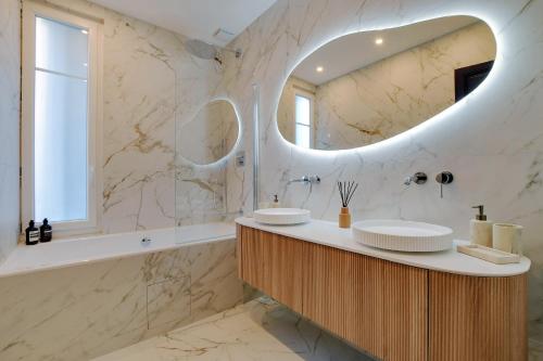 une salle de bain avec deux lavabos et un grand miroir dans l'établissement Parisian Suites, à Boulogne-Billancourt