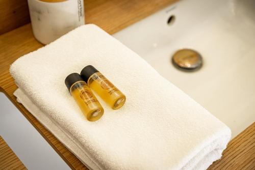 - deux bouteilles de médicaments assises sur une serviette sur un lavabo dans l'établissement Le Buffon - Elegance & Charm, à Dijon