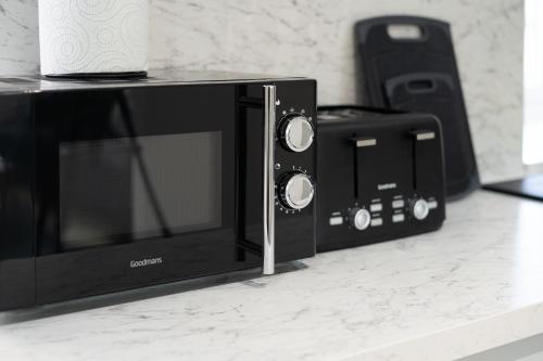 a microwave and a toaster oven on a counter at Modern 5 BED-2 BATH Apartment in Galashiels