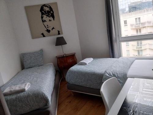a small bedroom with two beds and a window at Appartement la défense Courbevoie in Courbevoie