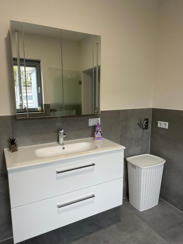 a bathroom with a white sink and a mirror at Moderne FerienWohnung NeuBau Merzig in Merzig